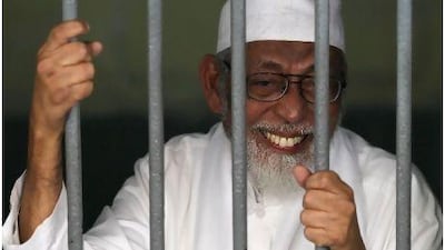 Islamic cleric Abu Bakar Bashir smiles as he talks to reporters from his cell before his trial in Jakarta.