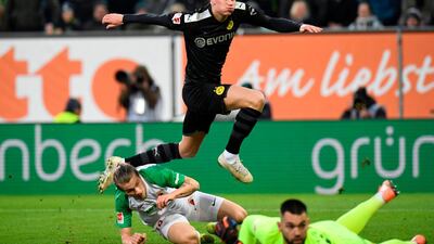 Erling Haaland jumps over Augsburg goalkeeper Tomas Koubek and defender Tin Jedvaj to score for Dortmund. AFP