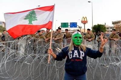 A Lebanese protester wears a mask and holds a national flag as other protesters block the highway leading to the presidential palace. The country could be on the verge of a social revolution. Wael Hamzeh / EPA