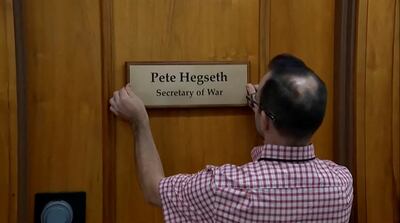 A worker installs the new sign outside Pete Hegseth's office. Reuters