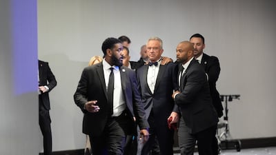 Law enforcement officers surround Robert F. Kennedy Jr. , US secretary of Health and Human Services (HHS), and his wife, actress Cheryl Hines following reports of a shooting during the White House Correspondents' Association (WHCA) dinner in Washington, DC, US on Saturday, April 25, 2026. President Donald Trump and Vice President JD Vance were evacuated from the White House Correspondents' Association dinner event in Washington Saturday following a security incident at the venue. Photographer: Yuri Gripas / Abaca / Bloomberg