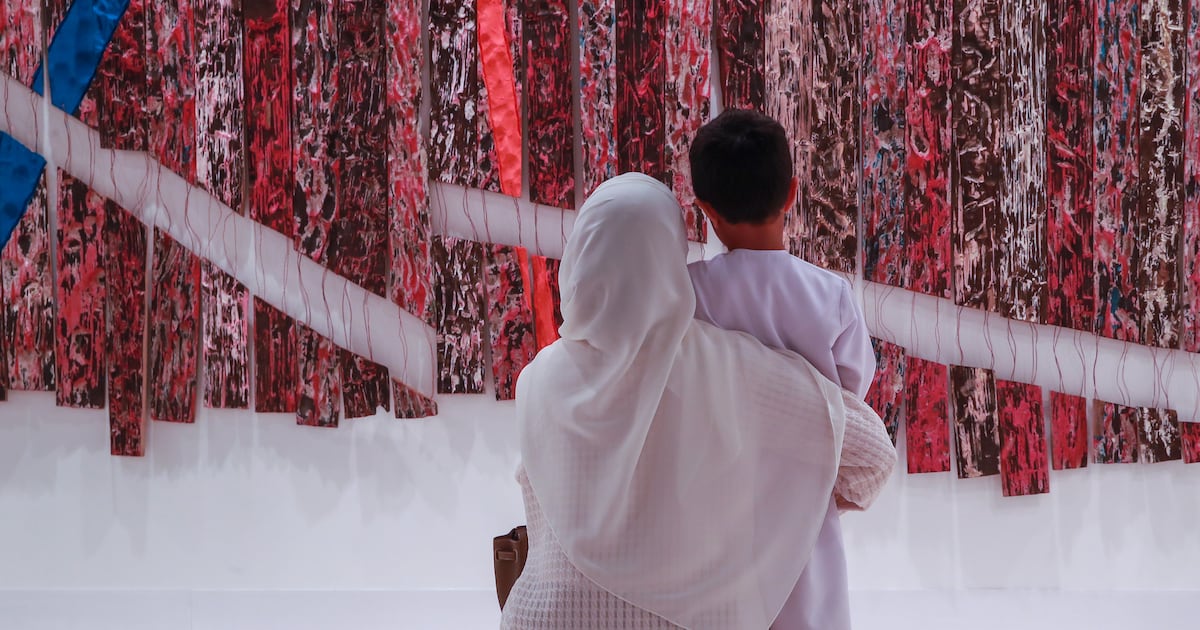 Photo: Thenationalnews A mother and son look at an artwork at Abu Dhabi Art 2023. The annual event has been rebranded as Frieze Abu Dhabi. Victor