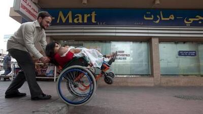 Accessibility to destinations for Neena Nizar is not always easy as her husband Adam Timm eases her and their two sons, Jahan and Arshaan off a curb near a local market outside the family's apartment in Al Karama.