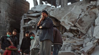 A Syrian civilian watches as civil defence volunteers work on recovering a body from the rubble of a building in the rebel enclave of Eastern Ghouta on March 5, 2018 on the outskirts of Damascus. Hamza Al-Ajweh / AFP