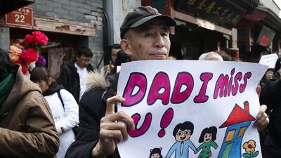 A relative holds a sign reading ‘Dad I miss U!’, outside the Yonghegong Lama Temple in Beijing. Rolex Dela Pena / EPA
