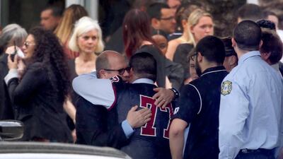 Mourners console each other during the funeral service for Marjory Stoneman Douglas High School assistant football coach, Aaron Feis. at the Church by the Glades in Coral Springs, Florida. Football players wearing Stoneman Douglas jerseys carried Feis' casket into the service at the church where family and friends gathered to remember him as loyal and caring. Mike Stocker/South Florida Sun-Sentinel via AP