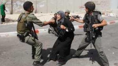A Palestinian woman scuffles with Israeli border police at Qalandia checkpoint near the West Bank city of Ramallah.