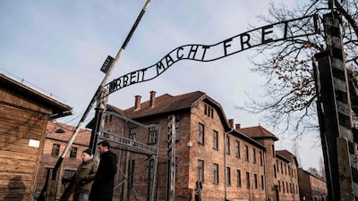 Holocaust survivor and former prisoner of the Nazi death camp Auschwitz-Birkenau, Johnny (Ephroim) Jablon (L), crosses the gate with the inscription reading "Work sets you free" (Arbeit macht frei) in Oswiecim on January 26, 2020, a day before the 75th anniversary of its liberation. Wojtek Radwanski / AFP