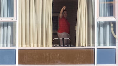 A traveller in compulsory quarantine gives the thumbs-down from her room at the Radisson Blu hotel near Heathrow Airport, London. Getty