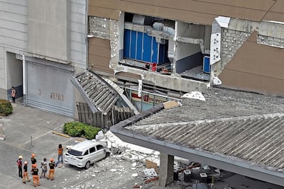 Authorities inspect a damaged wall and a car outside a mall in Butuan City, on the island of Mindanao, after a 7.4-magnitude earthquake struck off the southern Philippines on Friday. AFP