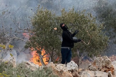 An Israeli settler casts a stone towards Palestinians, amid violence aimed at disrupting the Palestinian olive harvest, in Abu Falah, occupied West Bank. Reuters