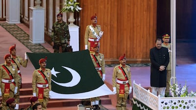 Pakistani soldiers carry the national flag prior to be hoisted by president Mamnoon Hussain, right, during a ceremony to mark the country's Independence Day in Islamabad. Aamir Qureshi / AFP Photo