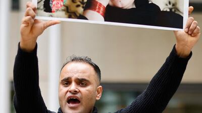 A former interpreter holds a placard displaying the message "protect our loved ones". AFP