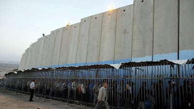Palestinians wait to cross into Jerusalem next to Israel's barrier at a checkpoint near Bethlehem. Ammar Awad / Reuters