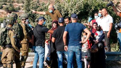 Palestinians are blocked by Israeli policemen and army soldiers, some clad in masks due to the Covid-19 pandemic, while on their way home at the entrance of a junction by the Palestinian village of Halhul, north of Hebron in the occupied West Bank, as Israeli settlers arrive to attend a rally against US President Donald Trump's peace plan. AFP