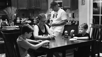 A family sits around a dinner table and look down where a smartphone would be. Courtesy Eric Pickersgill