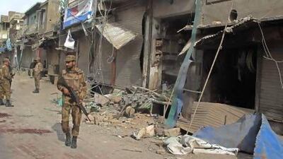 A security official walks in front of a damaged shop after a bomb exploded near a Shiite procession in Dera Ismail Khan in Pakistan's northwest.