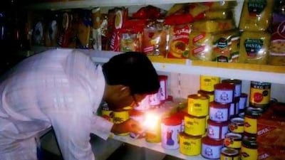 A supermarket employee inspects his wares by candlelight during a blackout in Sharjah last Tuesday.