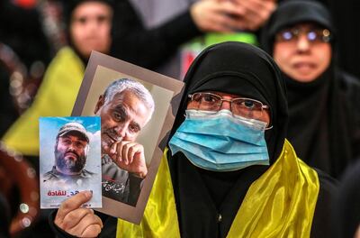 A Hezbollah supporter wears a medical mask while holding a photo of assassinated Iranian general Qassem Suleimani during a Martyrs' Day rally in Beirut on February 16. Nabil Mounzer / EPA