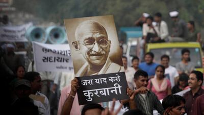 August 18, 2011: Indian supporters of anti-corruption activist Anna Hazare hold a portrait of Mahatma Gandhi as they protest against corruption in Ahmadabad, India. The Hindi slogan in center reads "Remember the sacrifice". Many have likened Anna Hazare t???