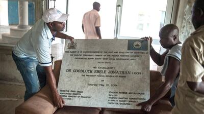 People carry a commemoration plaque for the International Diving School. The school was built by the ex-militant leader Government Ekpemupolo in an effort to boost educational opportunities in the Delta State and was bought by the Nigerian Government to act as a complementary facility to the Nigerian Maritime University in Okerenko. Stefan Heunis/AFP