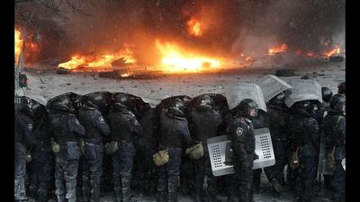 Interior Ministry members stand in formation in front of burning tyres set ablaze by pro-European protesters during clashes in Kiev. Reuters