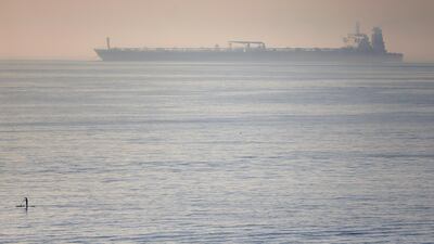 A man paddles on a surfboard near the Iranian oil tanker Grace 1 as it sits anchored after Gibraltar lifted the detention order. Reuters