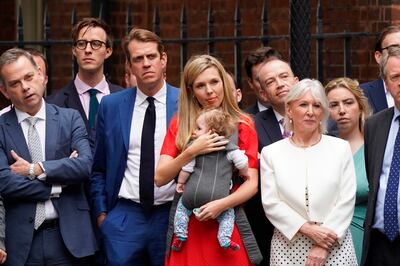 Carrie Johnson, the wife of British Prime Minister Boris Johnson, cradles their daughter Romy as she listens to him read a statement outside 10 Downing Street. AP.