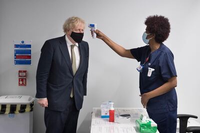 Prime Minister Boris Johnson has his temperature checked during a visit to view the vaccination programme at Chase Farm Hospital , London. Getty Images