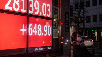 A woman stands in front of an electronic quotation board displaying the Nikkei 225 index of the Tokyo Stock Exchange. Nikkei was down 0.21 per cent on Friday after touching three-decade highs in the previous session. AFP