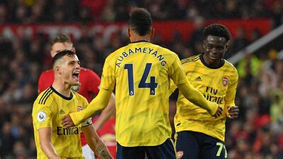 Arsenal's Gabonese striker Pierre-Emerick Aubameyang (C) celebrates with Arsenal's Swiss midfielder Granit Xhaka (L) and Arsenal's English striker Bukayo Saka (R) after scoring their first goal, decision of off-side overturned by VAR (Video Assistant referee) during the English Premier League football match between Manchester United and Arsenal at Old Trafford in Manchester, north west England, on September 30, 2019. RESTRICTED TO EDITORIAL USE. No use with unauthorized audio, video, data, fixture lists, club/league logos or 'live' services. Online in-match use limited to 120 images. An additional 40 images may be used in extra time. No video emulation. Social media in-match use limited to 120 images. An additional 40 images may be used in extra time. No use in betting publications, games or single club/league/player publications. / AFP / Paul ELLIS / RESTRICTED TO EDITORIAL USE. No use with unauthorized audio, video, data, fixture lists, club/league logos or 'live' services. Online in-match use limited to 120 images. An additional 40 images may be used in extra time. No video emulation. Social media in-match use limited to 120 images. An additional 40 images may be used in extra time. No use in betting publications, games or single club/league/player publications.