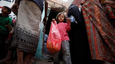 A child gets her family's free food ration from a charity group in Sanaa, Yemen. EPA