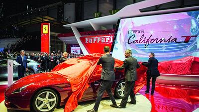 Ferrari president Luca Cordero di Montezemolo, left, looks on as men unveil the brand's latest car, the California T, at the Geneva Motor Show. AFP photo
