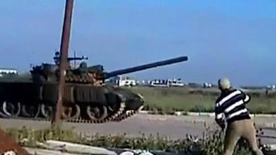 A video released by Sham News Network, a Syrian freedom group, shows a man throwing an object at a tank in Deraa on Sunday.