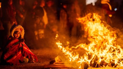 A child sits by a bonfire while members of the Ohkay Owingeh pueblo participate in the Matachinas dance in celebration of Christmas, San Juan Pueblo, New Mexico. AFP