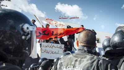 Young men and boys from Ettadhamen climbed atop construction debris to hold a banner over a crowd of riot police in full body armour who kept the group of protesters from reaching the Parliament building on January 26, 2021. Erin Clare Brown / The National