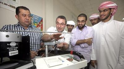 Electrical engineering professors Nasser Qaddooumi and Lutfi Albasha discuss details of the microchip they are developing with undergraduate students at the American University of Sharjah.