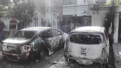 Security personnel stand next to burned out vehicles in front of the Chinese consulate in Karachi. AFP