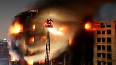 Firefighters are seen on a ladder, spray water to extinguish a fire on a multi-storey building, in Dhaka, Bangladesh. REUTERS