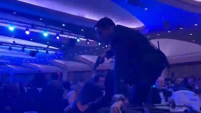 An armed agent climbs over chairs as he movse to the stage after loud bangs were heard during the White House Correspondents' dinner. AFP