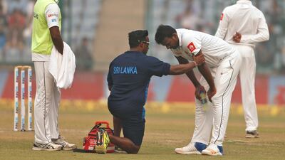 A paramedic speaks to Sri Lanka's Lahiru Gamage after he complained of short of breath during the second day of a third test cricket match against India in New Delhi. Altaf Qadri / AP Photo