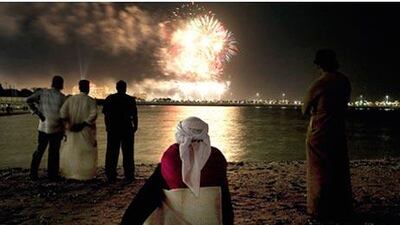 Ghader Ali Gabeer al Mansoory watches the fireworks with a flag draped over his shoulders along Abu Dhabi's Corniche.