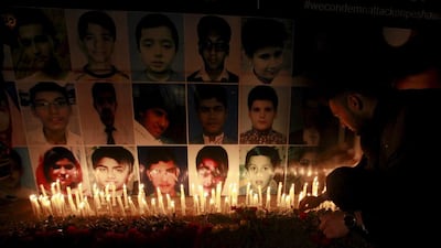 A man places a rose after lighting candles in front of portraits of the victims of the Taliban attack on the Army Public School in Peshawar. Pakistan has hanged four men linked to the December 2014 attack. Mohsin Raza / Reuters / December 19, 2014 file
