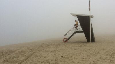 A lifeguard looks out at the fog covered empty Umm Suqeim beach. Kamran Jebreili / AP Photo
