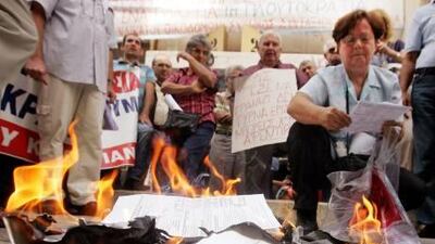 Members of a Greek trade union burn tax statements during a demonstration outside an Athens Tax Bureau. EPA