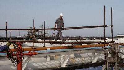Above, an Iranian worker walks on pipelines at an oil facility in Khark Island. AFP