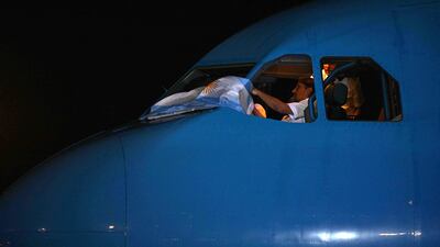 An Argentina flag is waved out of the plane's cockpit that brought the national team home from the Qatar World Cup. AFP