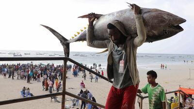 A Somali trader carries a fish at Liido beach in Mogadishu. Reuters