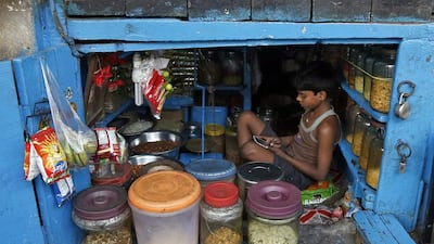 A boy uses a mobile phone as he sits inside his father’s snack shop in Kolkata. Rupak De Chowdhuri / Reuters