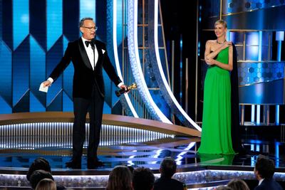 Tom Hanks accepts the Cecil B. DeMille Award as Charlize Theron looks on. Reuters